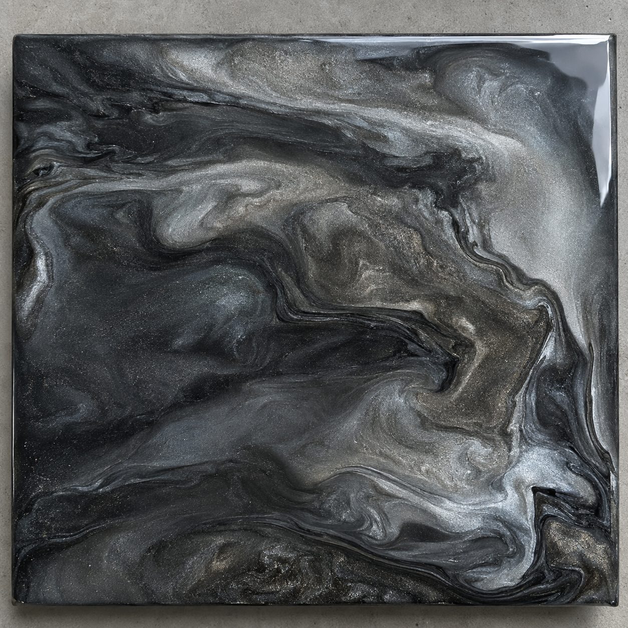 A metallic epoxy concrete floor coating sample with swirls of charcoal, pewter, and silver pigment.
